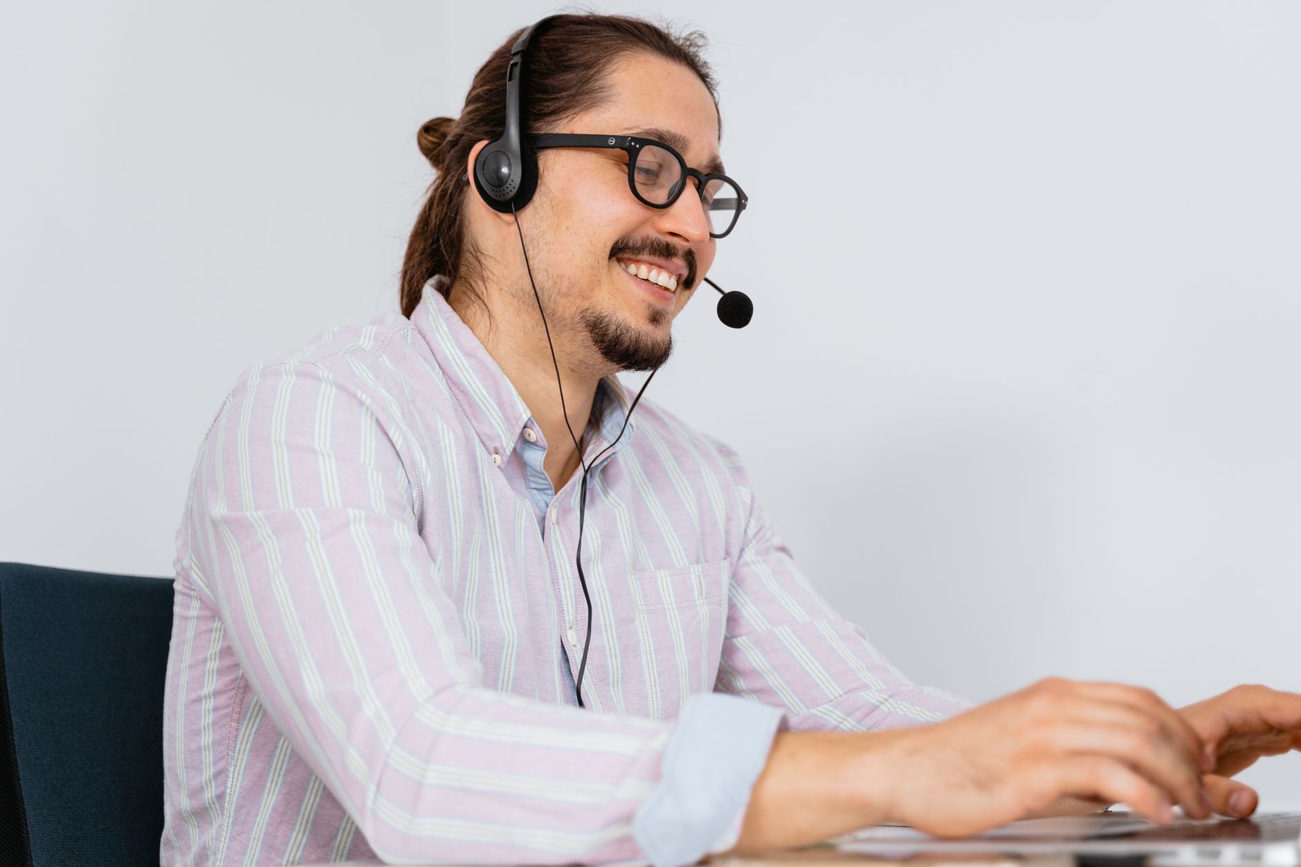 Atendente de call center sorridente, usando fone de ouvido, auxiliando clientes.