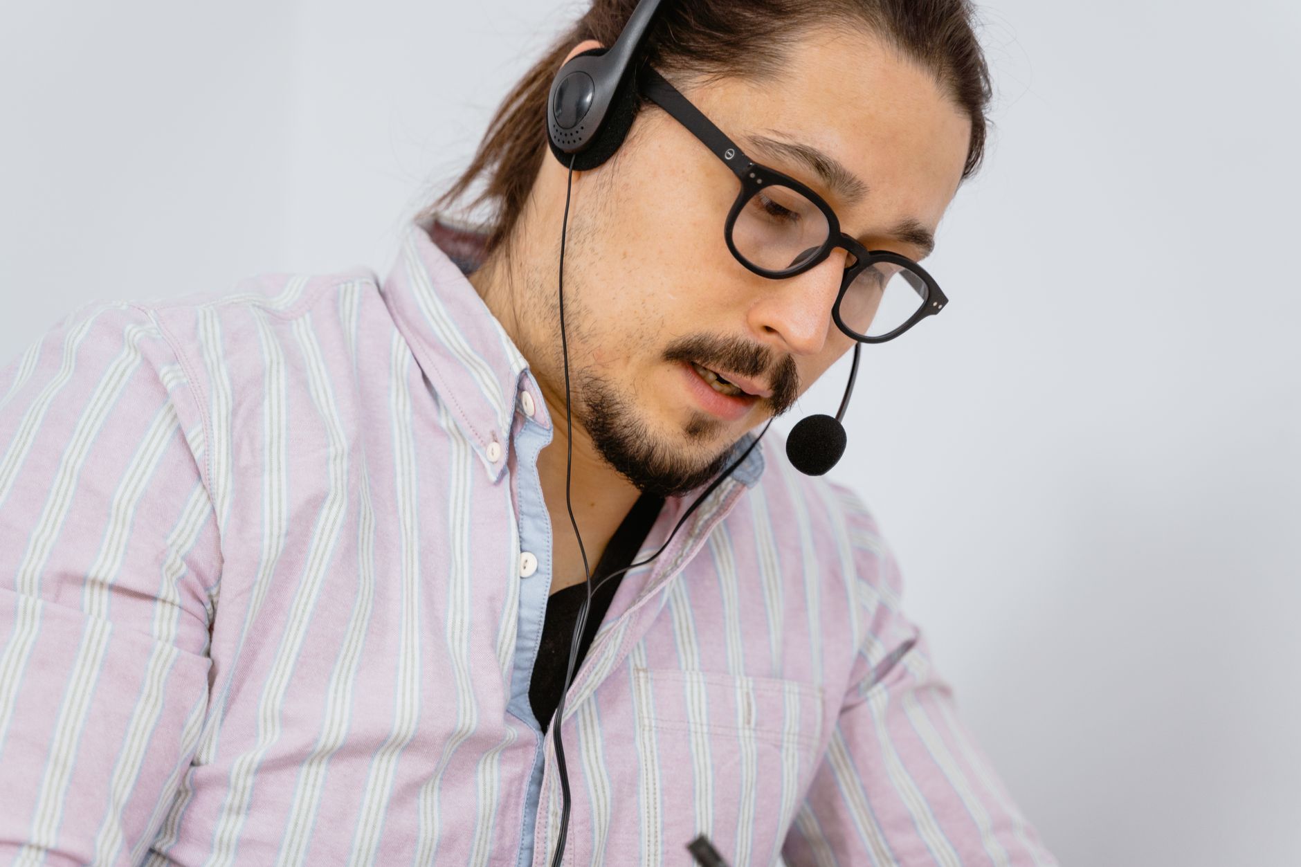 Atendente de call center concentrado, com fone de ouvido, prestando suporte ao cliente.